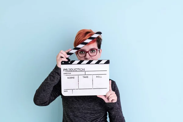 Woman holding movie clapper against cyan background — Stock Photo, Image