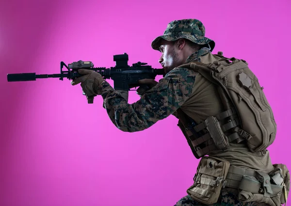 Soldier in action aiming laseer sight optics pink background — Stok fotoğraf