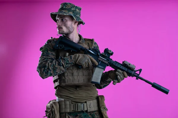 Soldado en acción apuntando laseer vista óptica fondo rosa — Foto de Stock