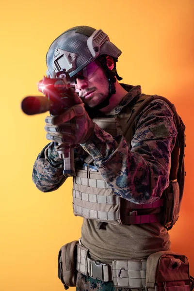 Soldaat in actie gericht op laserzicht optiek gele achtergrond — Stockfoto