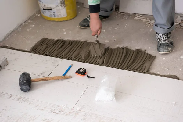 skilled worker installing the ceramic wood effect tiles on the floor Worker making laminate flooring on the construction site of the new apartment