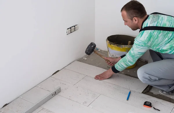 床にセラミックウッド効果タイルを設置する熟練労働者新しいアパートの建設現場に積層床を作る労働者 — ストック写真