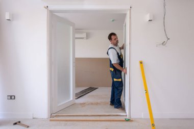 Erkek marangozlar, yeni lüks apartmana iç cam kapı döşüyorlar.