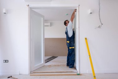 Erkek marangozlar, yeni lüks apartmana iç cam kapı döşüyorlar.