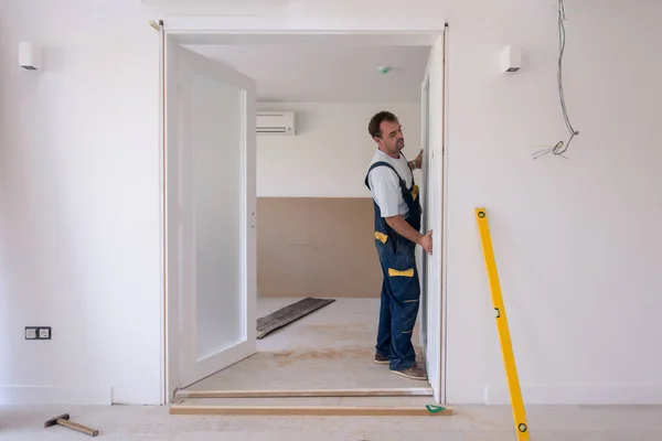 男性労働者カーペンター新しい高級アパートで木製のフレームとインテリアガラスのドアを設置 — ストック写真