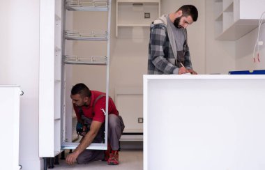İki profesyonel işçi yeni moda modern mutfak mobilyalarını kuruyor.