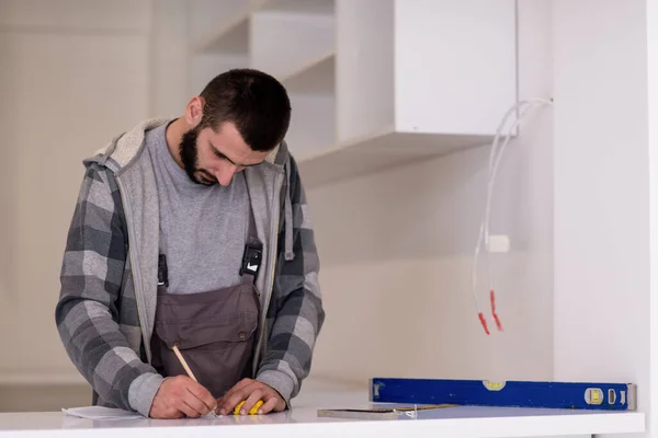 在安装新式现代厨房家具的过程中 年轻的专业工作人员写下了措施 — 图库照片