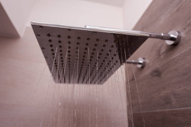Modern, paslanmaz çelik duş, banyo içinde su damlaları modern bir banyoda kare duş başlığından akan su.