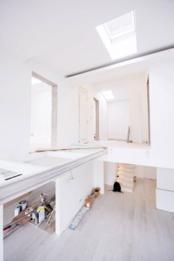 Boş, şık, modern, iki katlı, beyaz duvarları ve ortasındaki büyük, yuvarlak avizesi olan bir apartman dairesi.