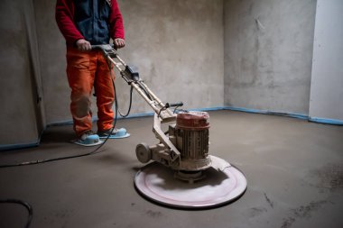 İşçi, yeni iki katlı bir apartmanın inşaat sahasında kum ve çimento döşeme işi yapıyor. Kum ve beton zemin perdelendi