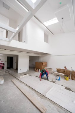 Seramik ahşap efekt fayanslarını döşeyen yetenekli bir işçi. İşçi, yeni apartmanın inşaat alanında döşeme kaplaması yapıyor.