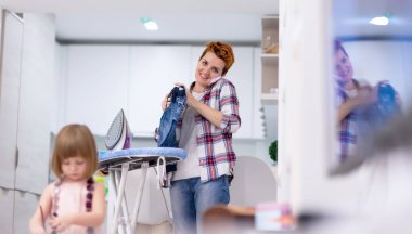 Mutlu bir aile, evde pembe elbiseli şirin bir kızla vakit geçirirken mücevher kutusunu boyar ve oynar. Bu arada genç kızıl saçlı anne de elbiselerini ütüler.