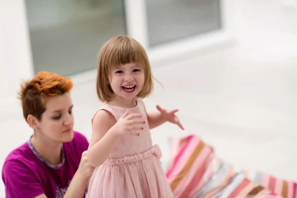 一家人在家里度过一个愉快的夜晚 年轻的妈妈一边帮可爱的小女儿干活 一边穿上粉红的衣服在家里跳舞 — 图库照片