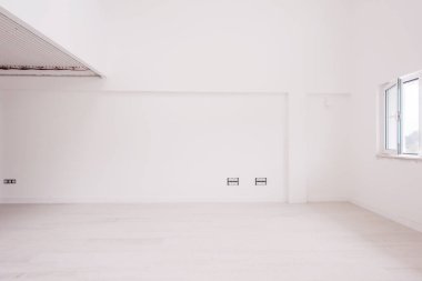 Boş, şık, modern, iki katlı, beyaz duvarları ve ortasındaki büyük, yuvarlak avizesi olan bir apartman dairesi.