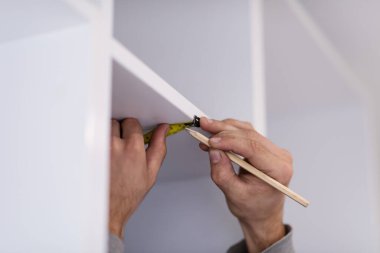 Yeni moda modern mutfak mobilyalarının montajı sırasında tedbirleri yazan genç profesyonel işçi