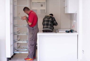 İki profesyonel işçi yeni moda modern mutfak mobilyalarını kuruyor.