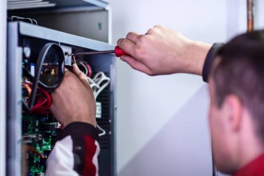 Modern sigorta kutusunun elektrik kablolarıyla çalışan elektrik mühendisinin yakın çekimi. Elektrik donanımı yeni voltaj kablolarını ayarlıyor
