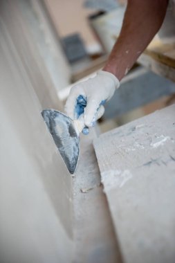 Genç profesyonel inşaat işçisi alçıtaşı duvarlara sıva yapıyor. Yeni, büyük, modern iki katlı apartmanın içinde.
