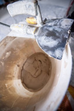 İnşaat araçlarının beton arka plandaki kovadaki üst görüntüsü. Çeşitli alçı mala araçları ve spatula seti