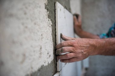Tecrübeli inşaat işçisi iç beton duvarlara büyük seramik fayanslar yerleştiriyor.