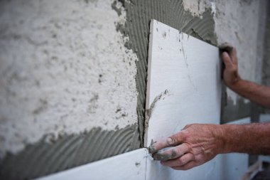 Tecrübeli inşaat işçisi iç beton duvarlara büyük seramik fayanslar yerleştiriyor.
