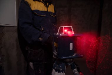 İnşaat halindeki bir binada lazer kullanan profesyonel bir işçi. İnşaat alanında lazer teçhizatı
