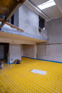İki katlı yeni bir apartmanın şantiyesinde beyaz polietilen boruları olan sarı yeraltı ısıtma tesisatı.