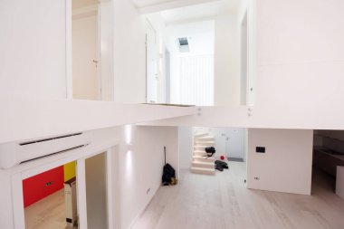 Boş, şık, modern, iki katlı, beyaz duvarları ve ortasındaki büyük, yuvarlak avizesi olan bir apartman dairesi.