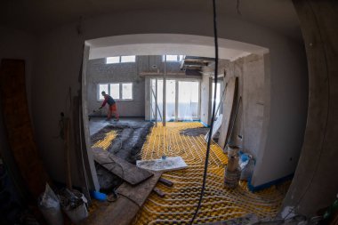 İşçi, yeni iki katlı bir apartmanın inşaat sahasında kum ve çimento döşeme işi yapıyor. Kum ve beton zemin perdelendi