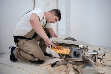 professional worker cutting plank with electrical circular saw during installation a new laminated wooden floor in a unfinished apartment clipart