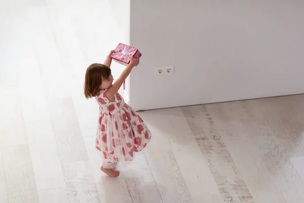 ピンクのドレス姿の可愛い可愛い女の子が家の床の上の箱からお母さんの宝石と遊びながら楽しんでる — ストック写真