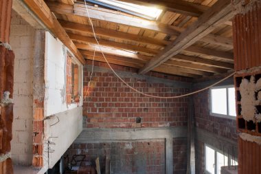 Pencereleri ve kırmızı tuğlalı inşaat alanı olan yeni iki katlı apartman dairesinin inşaatı devam ediyor.