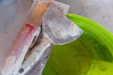 İnşaat araçlarının beton arka plandaki kovadaki üst görüntüsü. Çeşitli alçı mala araçları ve spatula seti