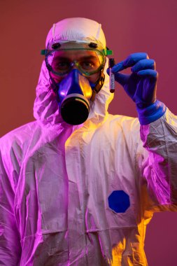 Coronavirus, doktorun elinde kovid 19 virüsü var. Kan örneği test tüpü. Biyolojik tehlike salgını maskesi, giysisi ve parlak ışık arkaplanı var.