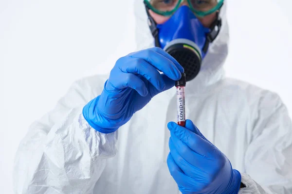 コロナウイルス 医師は正のCovid 19ウイルス血液サンプル検査管を保持します バイオハザードの流行を身に着けている白い背景に保護マスク スーツと手袋 — ストック写真