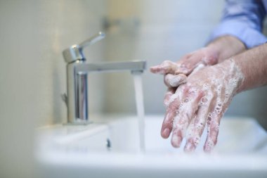 Coronavirus enfeksiyonu ve yayılan önleme sıvı sabunla düzgün yıkama elleri. Hijyen yanlısı erkek antibakteriyel eller banyoda yıkanır..