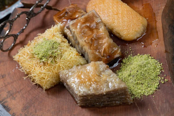ラマダーン カレーム 伝統的なトルコの中東のイフタールのお菓子ピスタチオと新鮮な蜂蜜を素朴な木製のプレートとヴィンテージブルーの背景テーブルの上にバクラバ トップ表示 — ストック写真