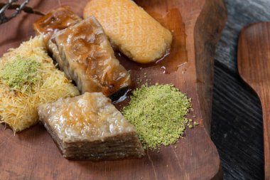 Ramazan Kareem, geleneksel Türk ortadoğu iftarı Baklava 'yı şam fıstıklı ve kır ağacından yapılmış ahşap tabakta taze bal ve klasik mavi arka plan masasıyla donatıyor. Üst görünüm.