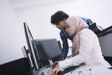Girişim işi, genç yaratıcı profesyoneller insanlar parlak ofiste buluşmayı tartışırken öneriler ve projede yardım için çift ekran bilgisayarına işaret ediyorlar.