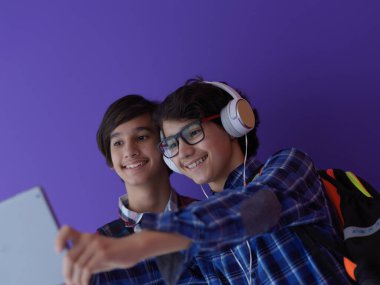 Takım olarak Arap gençler, öğrenciler dizüstü bilgisayar ve tablet bilgisayar kullanarak proje üzerinde birlikte çalışıyorlar. Eğitim kavramını mor arka planda tutuyorlar.