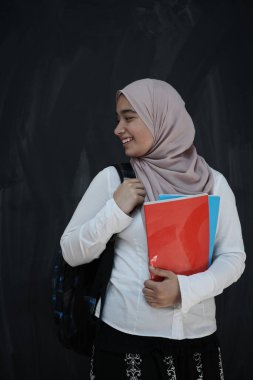 Orta Doğulu mutlu bir kız öğrencinin portresi sınıfta siyah karatahtaya karşı.