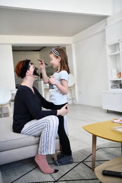 大肠病毒大流行期间在家中接受美容治疗的家庭留在家中进行检疫 妈妈和小女儿做了个面罩 — 图库照片