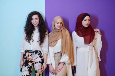 Güzel Müslüman kadınların grup portresi. İkisi şık giyimli, tesettürlü, renkli arka planda izole edilmiş. Modern İslam modasını ve Ramazan Kareem kavramını temsil ediyorlar.