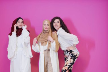 Güzel Müslüman kadınların grup portresi. İkisi şık giyinmiş. Pembe arka planda izole edilmiş. Modern İslam modasını ve Ramazan Kareem kavramını temsil ediyor.