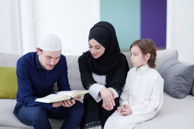 Geleneksel Müslüman aile ebeveynleri ve çocukları evde bir Ramazan şöleni sırasında iftar yemeğinden önce Kuran okuyup birlikte dua ediyorlar.