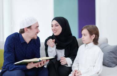 Geleneksel Müslüman aile ebeveynleri ve çocukları evde bir Ramazan şöleni sırasında iftar yemeğinden önce Kuran okuyup birlikte dua ediyorlar.