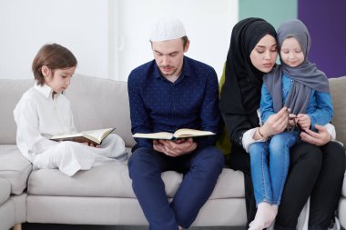 Geleneksel Müslüman aile ebeveynleri ve çocukları evde bir Ramazan şöleni sırasında iftar yemeğinden önce Kuran okuyup birlikte dua ediyorlar.