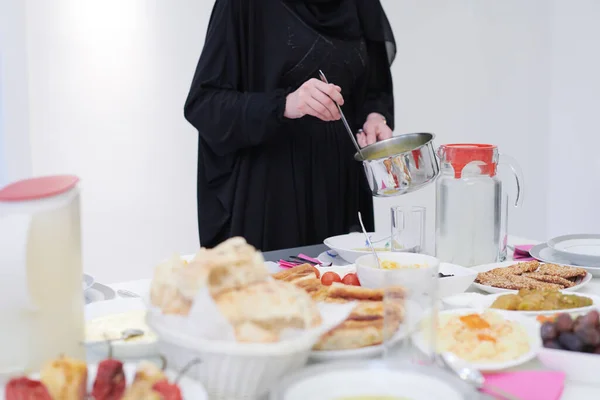 イフタールの夕食の若いイスラム教徒の女の子が家でラマダーンの祭りの月にテーブルの上で食べ物を提供しているイードムバラクイスラム教徒の家族 イスラム教のハラル食と飲酒 イスラーム家族 — ストック写真