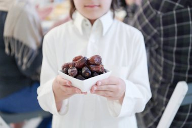 Mübarek Mübarek 'in ailesi iftar yemeği yiyorlar. Küçük çocuk ziyafeti kırmak için elinde bir tabak dolusu tatlı hurma tutuyor. Ramazan Bayramı 'nda evde geleneksel yemekler yemek. Modern Batı İslam 'da İslami helal yiyecekler ve içecekler.