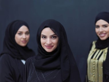 Modern İslami modayı ve Ramazan Kareem kavramını temsil eden siyah tesettürlü şık giyinmiş güzel Müslüman kadınların grup portresi.